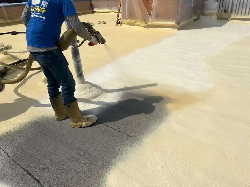 Installer spray-applying polyurethane foam over a commercial flat roof