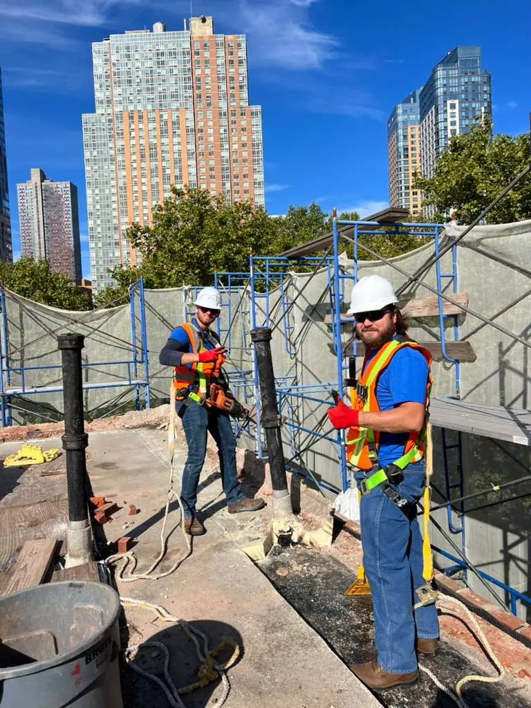 Commercial roofing crew wearing fall protection while preparing an urban roof