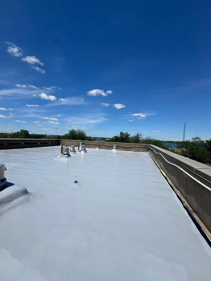 Completed reflective coating across an SPF commercial roof under a blue sky