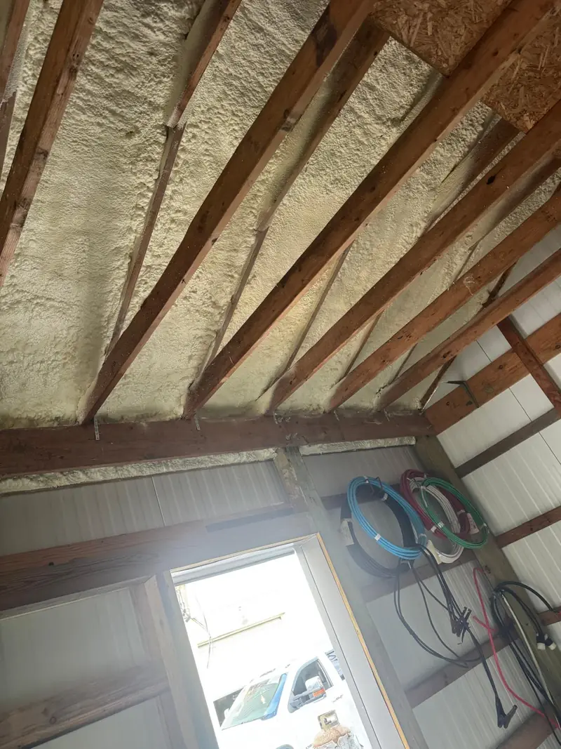 Spray foam insulation between framing beneath a metal building roof