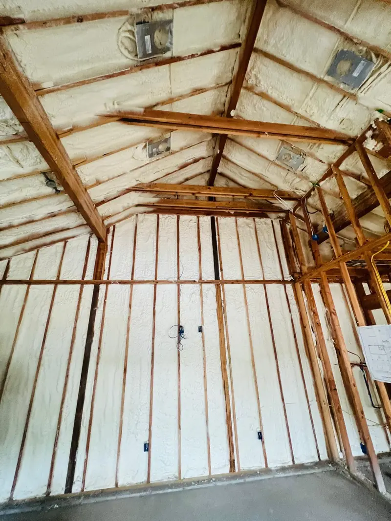 Spray foam insulation covering residential walls and a pitched roof assembly