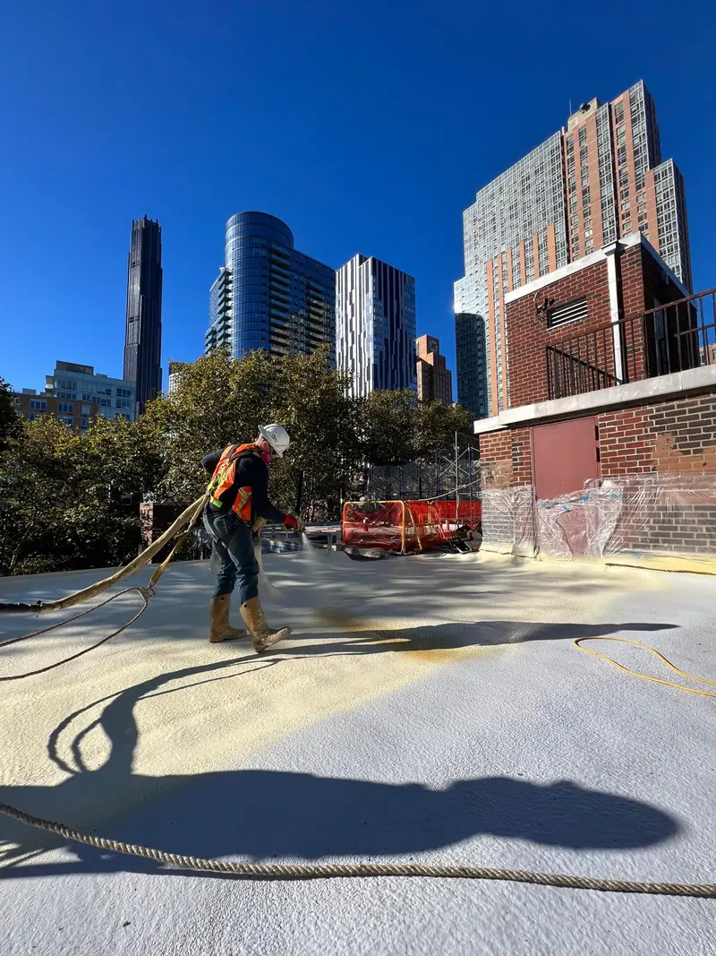 Crew installing spray polyurethane foam on an urban commercial flat roof
